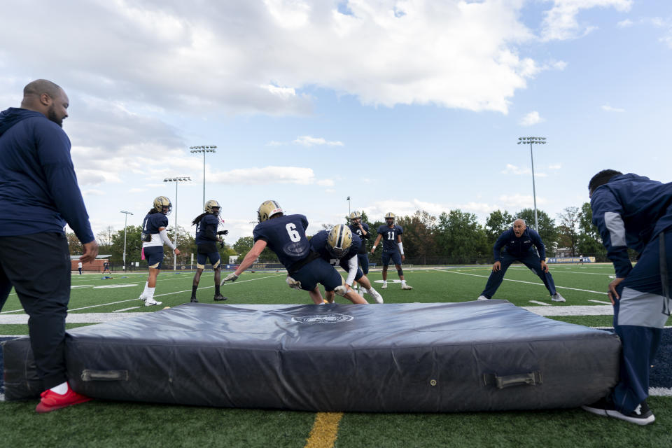 Gallaudet defensive players practice tackling drills during football practice at Hotchkiss Field, Tuesday, Oct. 10, 2023, in Washington. Gallaudet has been playing football since 1883, when it was known as the National Deaf-Mute College, and invented the huddle roughly a decade later. The school added a drum to replace whistles in 1970, and now present-day players and coaches carry on the program's rich history by winning games and continuing to innovate, most recently a helmet developed with AT&T that allows play calls to show up visually on a lens inside. (AP Photo/Stephanie Scarbrough)