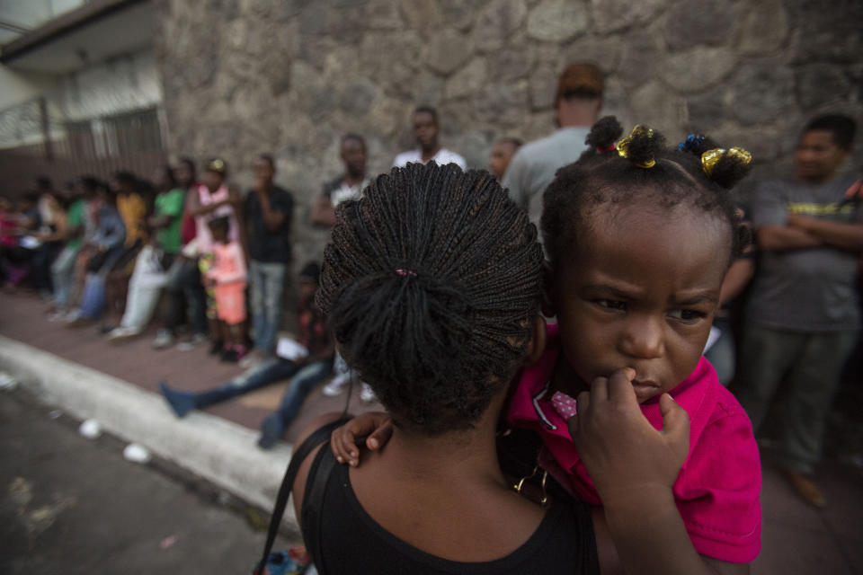 A Haitian woman carries her daughter as she waits outside the Mexican Commission for Migrant Assistance office, to get the documents needed that allow them to stay in Mexico, in Tapachula, early Thursday, June 20, 2019. The flow of migrants into southern Mexico has seemed to slow in recent days as more soldiers, marines, federal police, many as part of Mexico's newly formed National Guard, deploy to the border under a tougher new policy adopted at a time of increased pressure from the Trump administration. (AP Photo/Oliver de Ros)