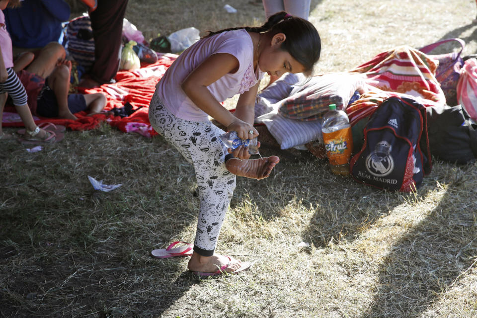 A girl cleans her feet at a temporary shelter for Honduran migrants in Tecun Uman, Guatemala in the border with Mexico, Sunday, Jan. 19, 2020. Mexican authorities have closed a border entry point in southern Mexico after thousands of Central American migrants tried to push across a bridge between Mexico and Guatemala. (AP Photo/Moises Castillo)