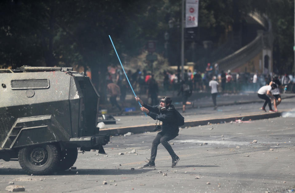 A demonstrator holds a stick to hit an armored vehicle during a protest against Chile's state economic model in Santiago, Chile on Oct. 23, 2019. (Photo: Ivan Alvarado/Reuters)