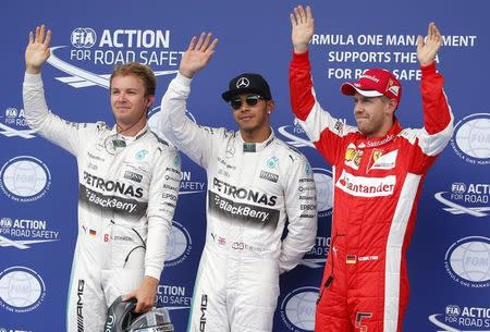 Mercedes Formula One driver Lewis Hamilton is flanked by Ferrari driver Vettel of Germany and team mate Nico Rosberg of Germany (L) following the qualifying session for the Austrian F1 Grand Prix in Spielberg, Austria, June 20, 2015. REUTERS/Laszlo Balogh