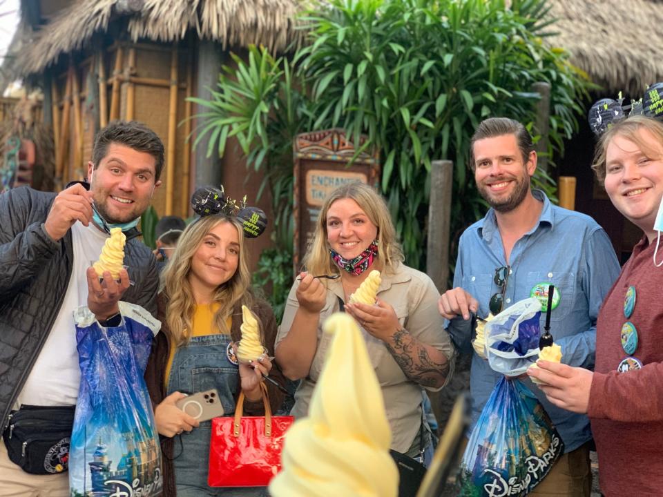 group of people eating dole whip in front of enchanted tiki room at disney world