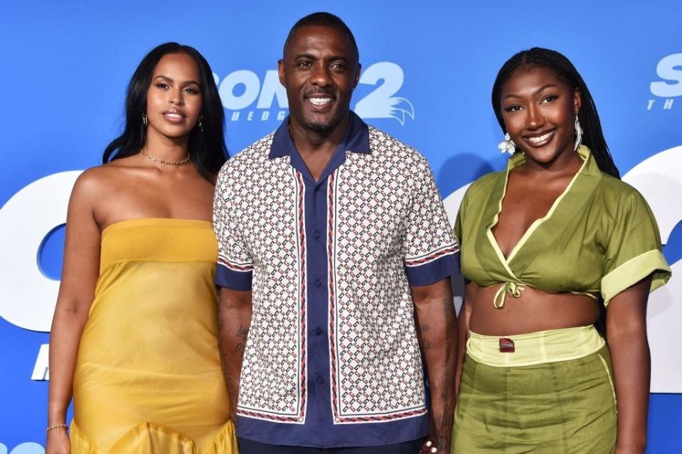 Idris smiles for photographers on the red carpet as he's flanked by his wife and daughter