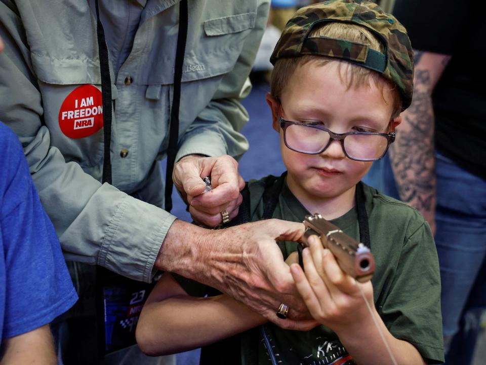 Hudson Eckart, 6, from Indiana, tries out a handgun with his grandfather Daniel Eckart during the National Rifle Association (NRA) annual convention in Indianapolis, Indiana.
