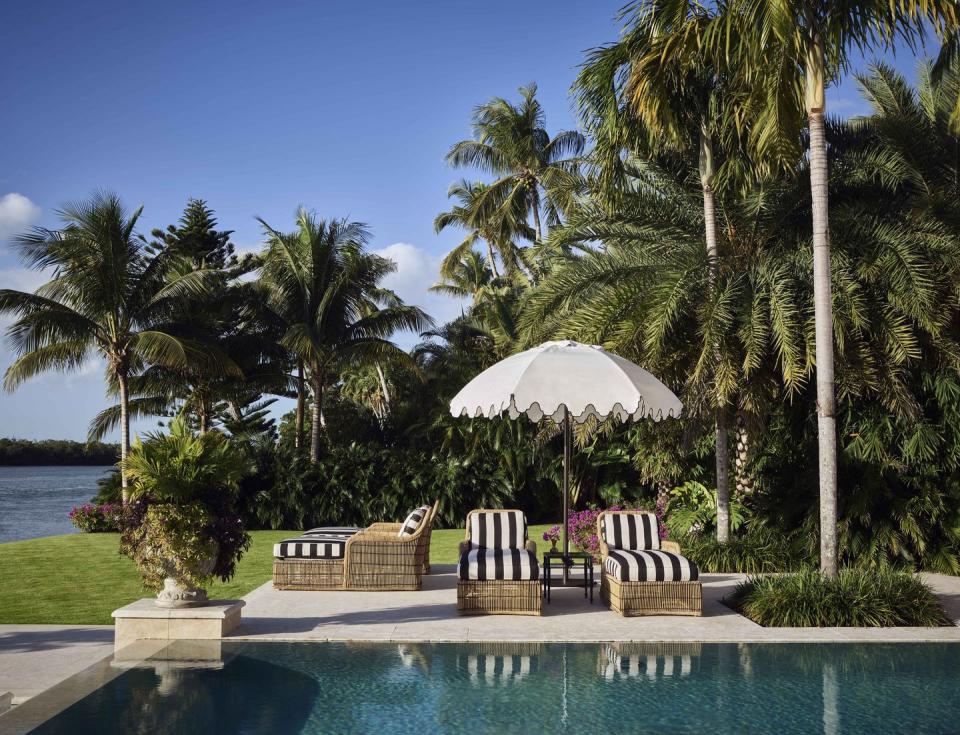 poolside view of black and white striped loungers and a white umbrella