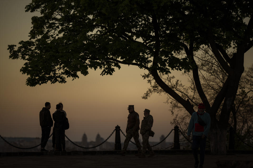 Two men from the Ukrainian territorial defence forces patrol at a public park as the sun sets in Kyiv Ukraine on Tuesday, May 10, 2022. (AP Photo/Emilio Morenatti)