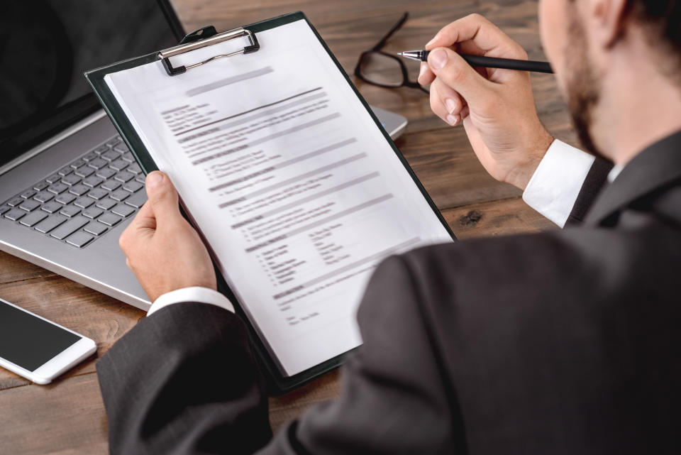 Employer assessing candidate filling form sitting in office back view close-up