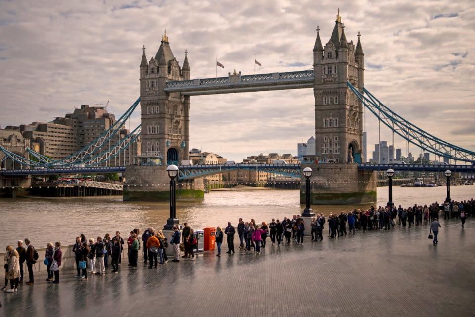 Aquellos en la larga fila para ver el funeral de la Reina pasan por Tower Bridge (AP)