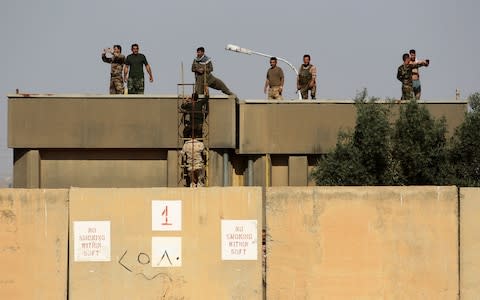 Kurdish peshmerga fighters stand on the roof top of a building as they hold a position on the opposition side of river bank from Iraqi forces on the southern outskirts of Kirkuk  - Credit: AFP