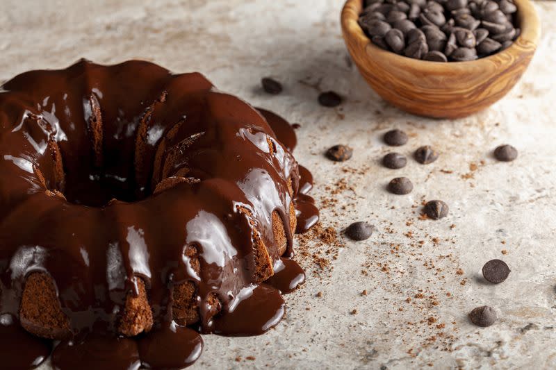 Angled view of a chocolate bundt cake with chocolate pudding icing dripping on top of it.