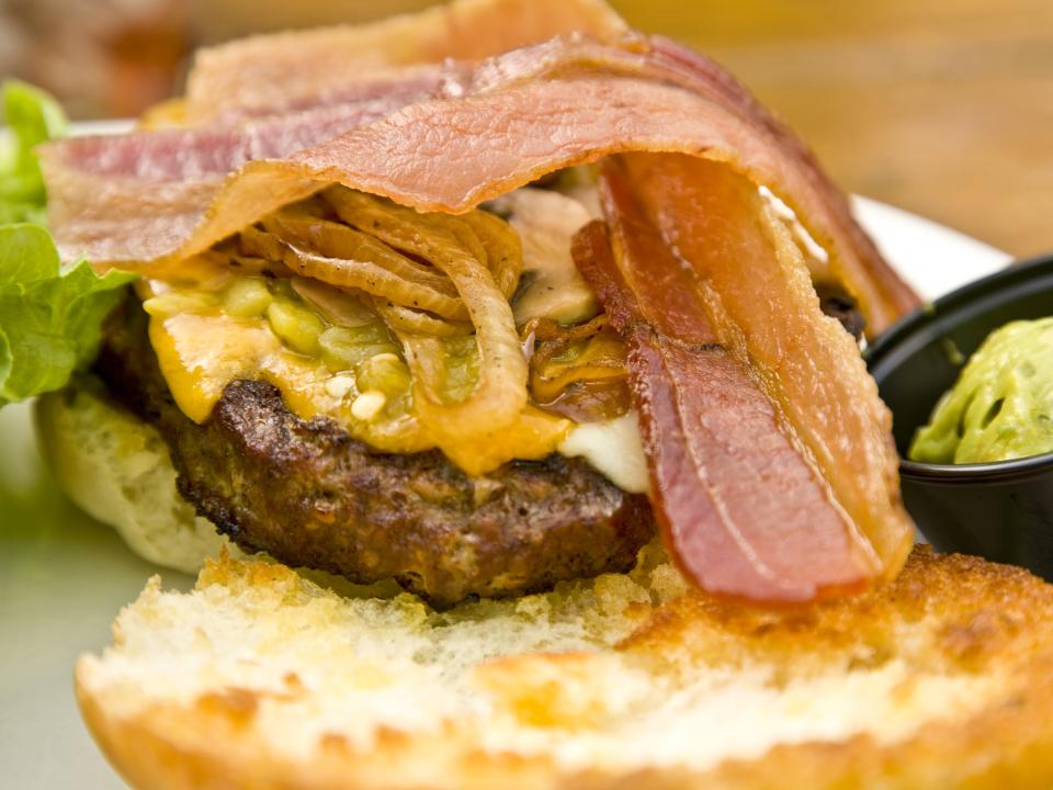 burger topped with bacon, cheese, and green chile