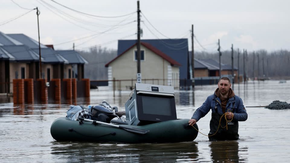 A man tows an inflatable boat holding his belongings along a flooded street in the Orenburg region. - Maxim Shemetov/Reuters