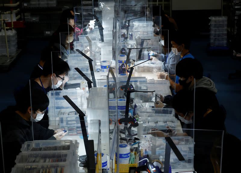 Workers clean used iPhones at an operations centre of Belong Inc, in Zama