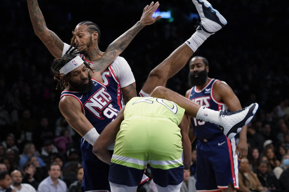 Brooklyn Nets guard DeAndre' Bembry (95) falls over Minnesota Timberwolves forward Josh Okogie (20) during the first half of an NBA basketball game Friday, Dec. 3, 2021, in New York. (AP Photo/Mary Altaffer)