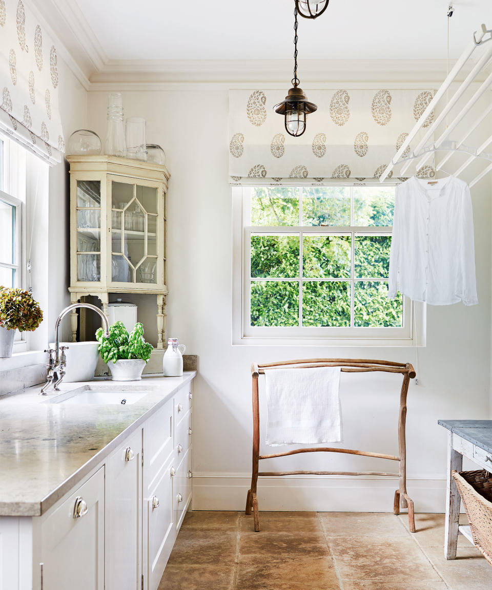 How to organize a laundry room, with a pulley drying rack, wooden clothes rail and stone countertop in a neutral and white scheme.