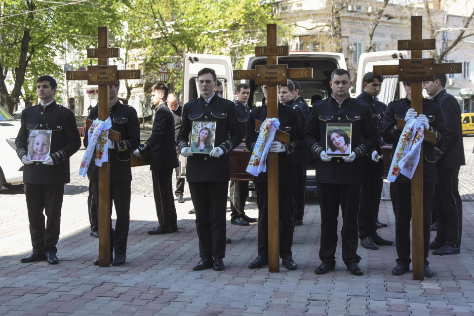 Men hold portraits of from left: Kira Glodan, three-month-old, her mother Valerya Glodan, 28, and grandmother Lyudmila Yavkina, 54, killed in their apartment by shelling, during a funeral ceremony at the Transfiguration Cathedral in Odessa, Ukraine, Wednesday, April 27, 2022. According Ukrainian officials five people including a three-month-old infant were killed and 18 injured in a missile attack in the Black Sea port city of Odesa on last Saturday, April 23. (AP Photo/Max Pshybyshevsky)