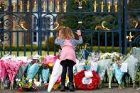 Una nilma mira por la reja del Castillo de Hillsborough junto a las flores depositadas en memoria del príncipe Felipe, en Hillsborough, Irlanda del Norte.