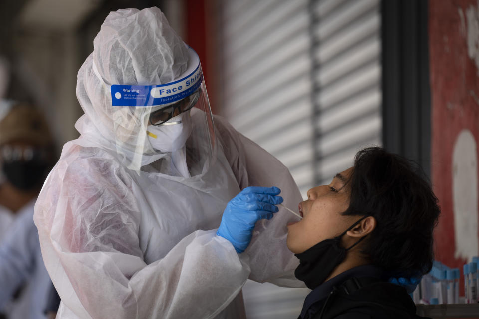 A doctor collects a sample for a coronavirus test outside a clinic in Kajang on the outskirts of Kuala Lumpur, Malaysia, Friday, Oct. 23, 2020. Malaysia restricted movements in its biggest city Kuala Lumpur, neighbouring Selangor state and the administrative capital of Putrajaya from Wednesday in an attempt to curb a sharp rise in coronavirus cases. (AP Photo/Vincent Thian)