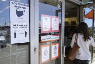 A customer enters a store with a face mask required sign displayed Tuesday, March 2, 2021, in Dallas. Texas is lifting a COVID-19 mask mandate that was imposed last summer but has only been lightly enforced. Republican Gov. Greg Abbott’s announcement Tuesday makes Texas the largest state to do away with a face covering order. (AP Photo/LM Otero)