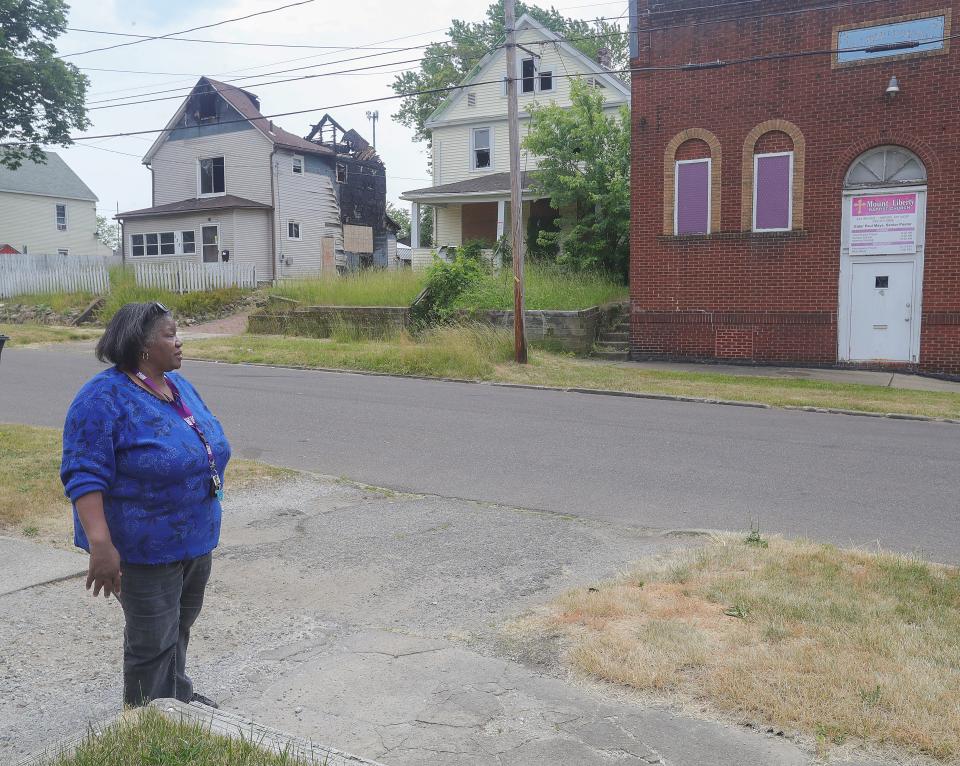 Summit Lake resident Sandra Saulsberry stands in her Ira Avenue driveway with a view of two burned out homes.