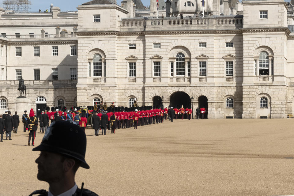 LONDON, ENGLAND - SEPTEMBER 14:  People watch from windows as ceremonial troops escort the gun carriage carrying Queen Elizabeth II's coffin across Horse Guards Parade during the procession from Buckingham Palace to the Palace of Westminster on September 14, 2022 in London, England. Queen Elizabeth II's coffin is taken in procession on a Gun Carriage of The King's Troop Royal Horse Artillery from Buckingham Palace to Westminster Hall where she will lay in state until the early morning of her funeral. Queen Elizabeth II died at Balmoral Castle in Scotland on September 8, 2022, and is succeeded by her eldest son, King Charles III. (Photo by Bryn Colton/Getty Images)