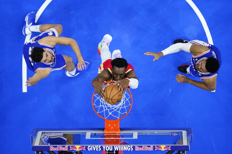 Atlanta Hawks' Onyeka Okongwu, center, dunks the ball past Philadelphia 76ers' Georges Niang, left, and Tobias Harris during the second half of an NBA basketball game, Monday, Nov. 28, 2022, in Philadelphia. (AP Photo/Matt Slocum)