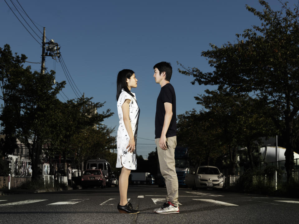 young japaneese couple standing in the middle of the street, looking at each other