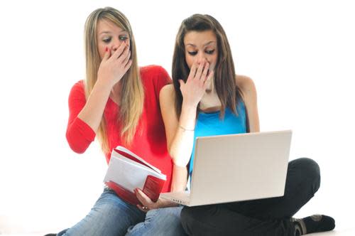 Girls looking shocked at image on laptop