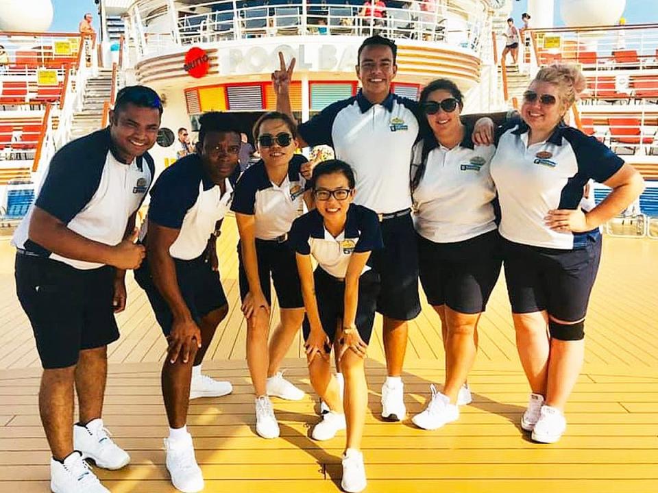 cruise ship staff posing for a photo on the deck of the ship