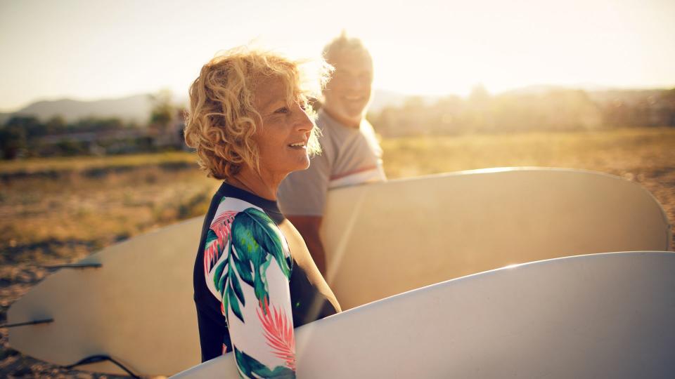 Very active senior couple getting ready to surf the waves on their active vacation.