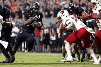 North Carolina State's Delbert Mimms III (34) tries to get past Louisville's Jaylin Alderman (24) during the first half of an NCAA college football game in Raleigh, N.C., Friday, Sept. 29, 2023. (AP Photo/Karl B DeBlaker)