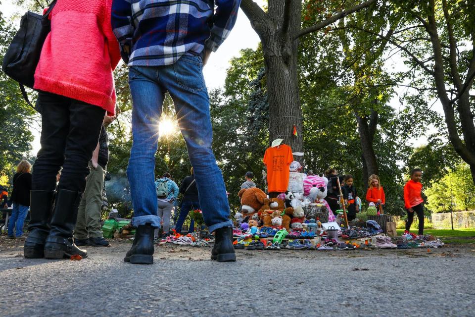 People pause to give their respect at a memorial after 215 graves were detected on the grounds of the former Kamloops Residential School at an event organized by 1492 Land Back Lane in Dufferin Grove Park, Toronto, on Sept. 30, 2021. THE CANADIAN PRESS/Evan Buhler