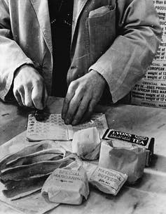 <span class="caption">A shopkeeper cancels the coupons in a British housewife’s ration book in 1943.</span> <span class="attribution"><a class="link " href="https://en.wikipedia.org/wiki/Rationing_in_the_United_Kingdom#/media/File:WWII_Food_Rationing.jpg" rel="nofollow noopener" target="_blank" data-ylk="slk:Library of Congress;elm:context_link;itc:0;sec:content-canvas">Library of Congress</a></span>