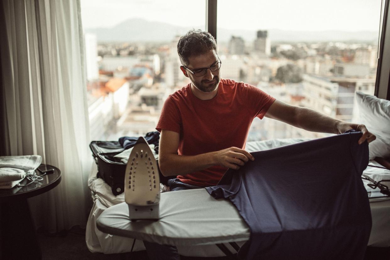 guy ironing in hotel room