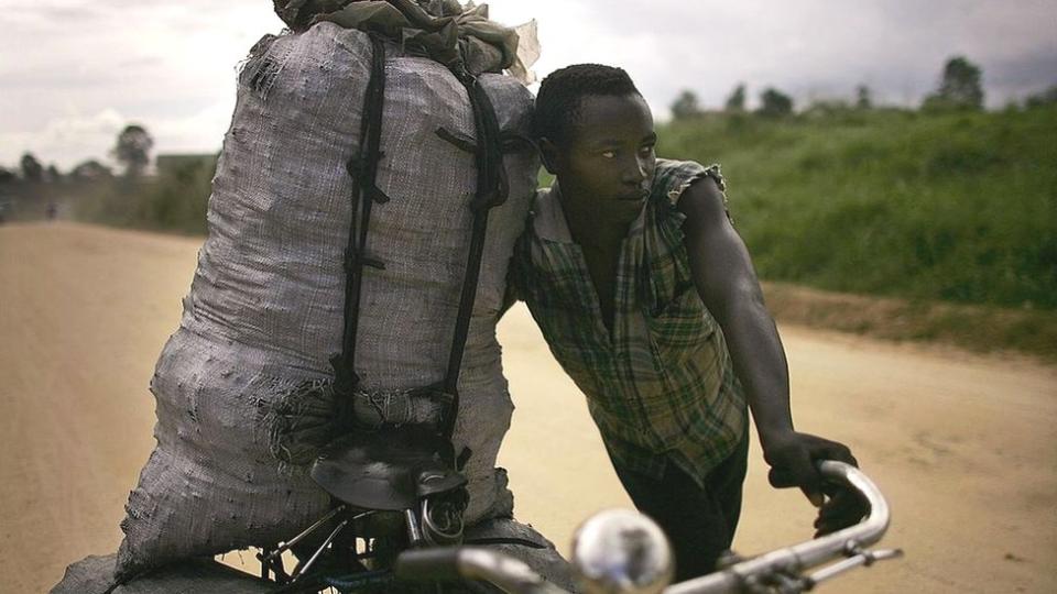 Joven con bolsa de carbón en bicicleta.