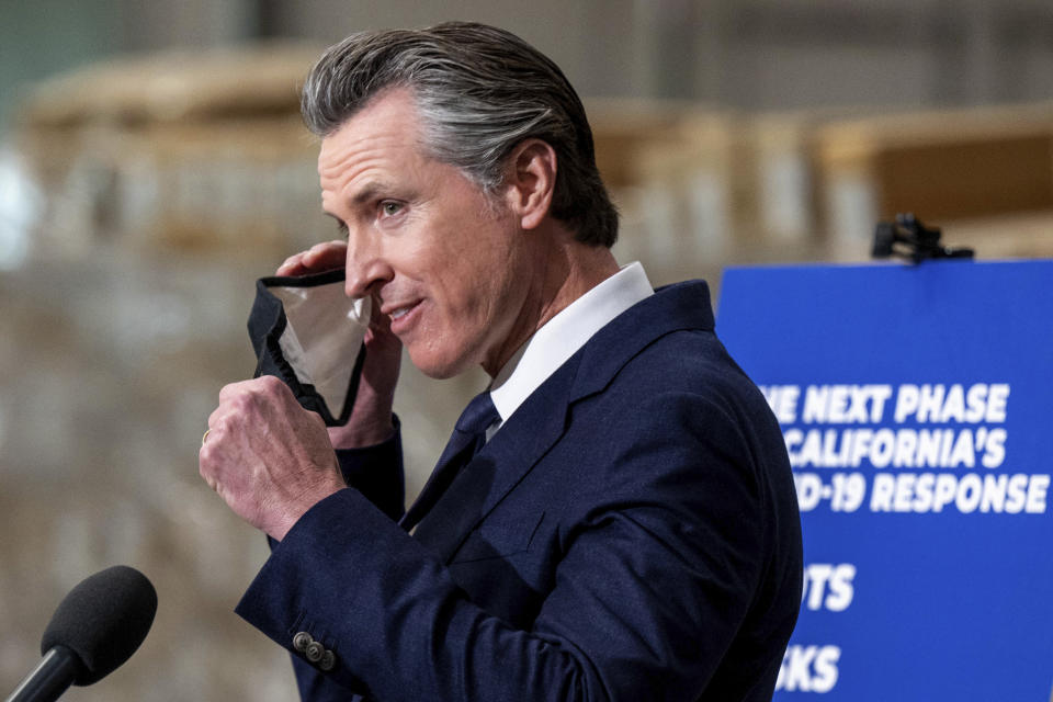 Gov. Gavin Newsom removes his face mask before speaking at a press conference to announce the next phase of California's COVID-19 response called "SMARTER," at the UPS Healthcare warehouse in Fontana, Calif., Thursday, Feb. 17, 2022. The plan is to move from the pandemic stage into an endemic stage in which people will learn to live COVID. (Watchara Phomicinda/The Orange County Register/SCNG via AP)