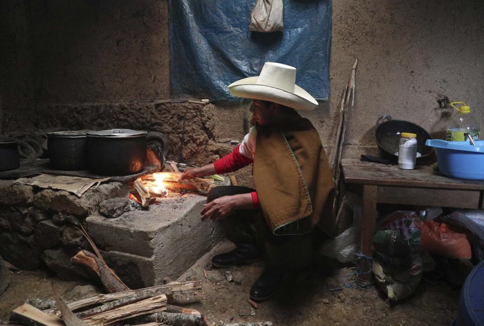 Free Peru party presidential candidate Pedro Castillo cooks breakfast for his family in his home in Chugur, Peru, Friday, April 16, 2021. Castillo, a rural teacher, who has proposed rewriting Peru's constitution and deporting all immigrants living in the country illegally who commit crimes, will face rival candidate Keiko Fujimori in the June 6 presidential run-off election. (AP Photo/Martin Mejia)