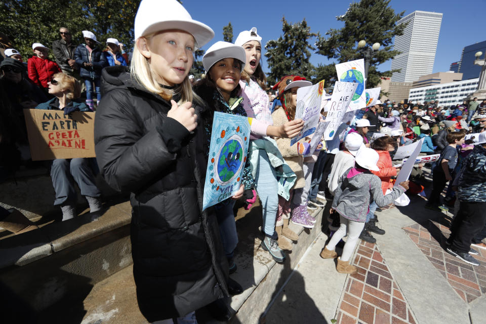 Harper Clonts, front, and Simalna Gonzalez-Robinson, both 9 and from Denver, wave placards as Swedish climate activist Greta Thunberg speaks to several thousand people at a climate strike rally Friday, Oct. 11, 2019, in Denver. The rally was staged in Denver's Civic Center Park. (AP Photo/David Zalubowski)