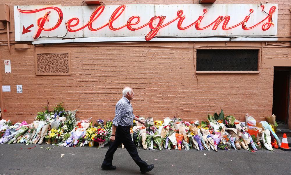 A man walks past floral tributes outside of Pellegrini’s