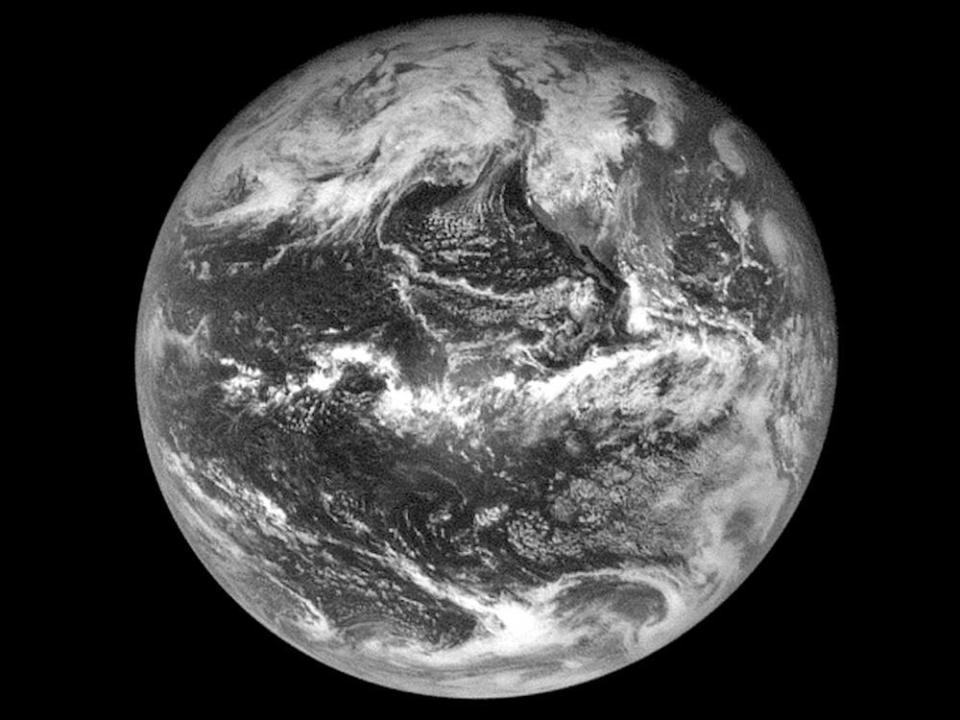 A photo of the Earth taken by NASA’s OSIRIS-REx spacecraft in black-and-white showing cloud cover