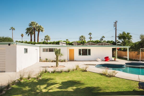 Set behind a bordering concrete wall, the historic home extends a warm welcome with its bright yellow main entrance and curvy, saltwater pool awaiting in the front yard.