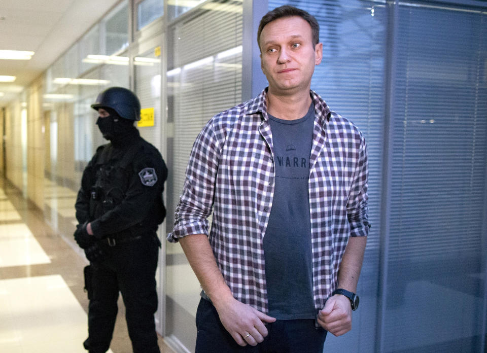 FILE - In this Dec. 26, 2019, file photo, Russian opposition leader Alexei Navalny speaks to the media in front of a security officer standing guard at the Foundation for Fighting Corruption office in Moscow, Russia. Russian opposition leader Alexei Navalny was the victim of an attack and poisoned with the Soviet-era nerve agent Novichok, the German government said Wednesday, Sept. 2, 2020 citing new test results. Navalny, a politician and corruption investigator who is one of Russian President Vladimir Putin's fiercest critics, fell ill on a flight back to Moscow from Siberia on Aug 20 and was taken to a hospital in the Siberian city of Omsk after the plane made an emergency landing. (AP Photo/Alexander Zemlianichenko, File)