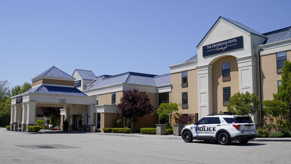 FILE - A town of Newburgh, N.Y., police vehicle is parked outside as security and staff personnel mill about The Crossroads Hotel where two busloads of migrants arrived hours earlier, May 11, 2023, in Newburgh, N.Y., in Orange County. New York City sued nearly half the state's counties Wednesday, June 7, over their attempts to keep out international migrants, the latest escalation in an ongoing battle between city officials and local leaders. (AP Photo/John Minchillo, File)