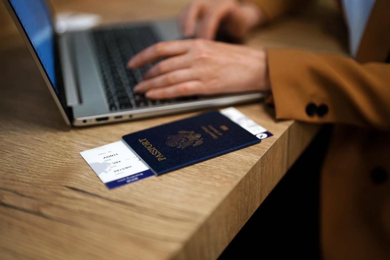 PHOTO: A woman with a U.S. passport waits for her flight while working on her laptop. (STOCK PHOTO/Adobe Stock)