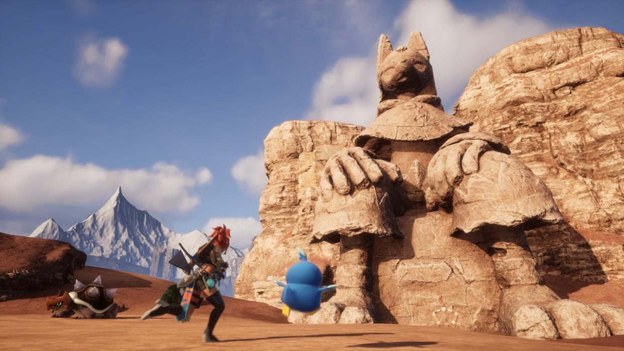  Players advance towards a large ancient statue in the desert. 