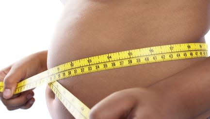 Childhood obesity. Boy measuring his stomach with a measuring tape. Childhood obesity is an increasing problem in the United Sta