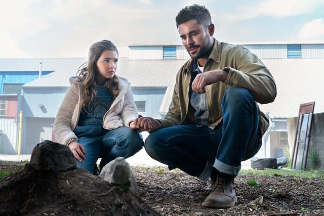 Ryan Kiera Armstrong and Zac Efron sit in front of a grave in Firestarter (2022)