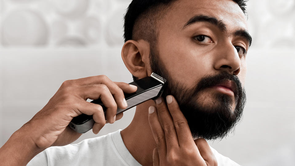 Handsome bearded man shaving his beard