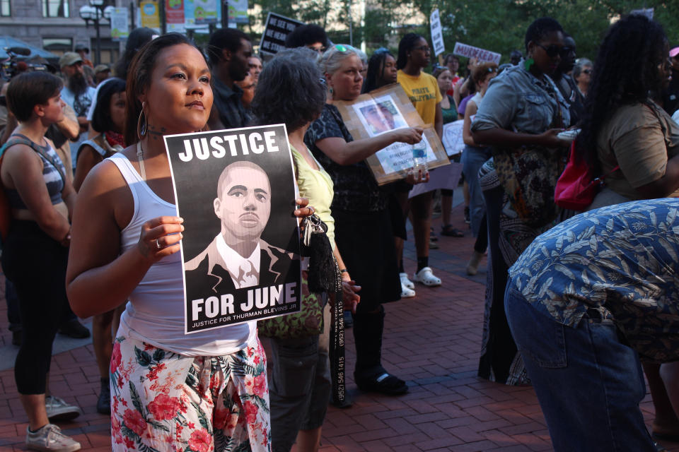 A woman holds a sign with a picture of Thurman "June" Blevins during a protest in downtown Minneapolis on Tuesday, July 31, 2018, over a prosecutor's decision not to charge two police officers who fatally shot Blevins last month. Activists and family members of the black man who was fatally shot by Minneapolis police marched through downtown Tuesday, blocking trains and intersections during the evening rush hour as they chanted some of Thurman Blevins' last words: "Please don't shoot me! Leave me alone!" (AP Photos/Jeff Baenen)