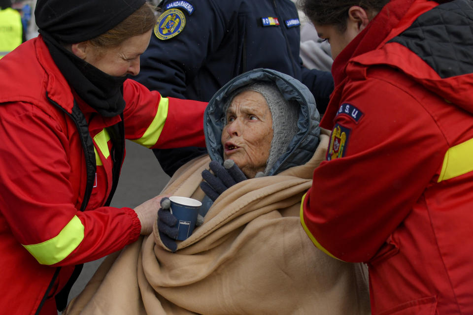 Emergency Situations Department employees talk to wheelchair user Katia, 90 years-old, a refugee fleeing the conflict from neighbouring Ukraine at the Romanian-Ukrainian border, in Siret, Romania, Saturday, March 5, 2022. (AP Photo/Andreea Alexandru)